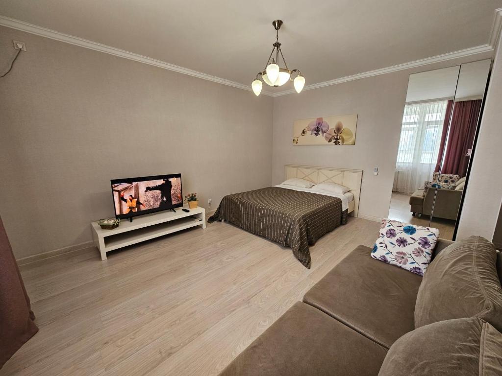 um quarto com uma cama, uma televisão e um sofá em Ernaz Plus Apartments: Promenade Expo em Astana