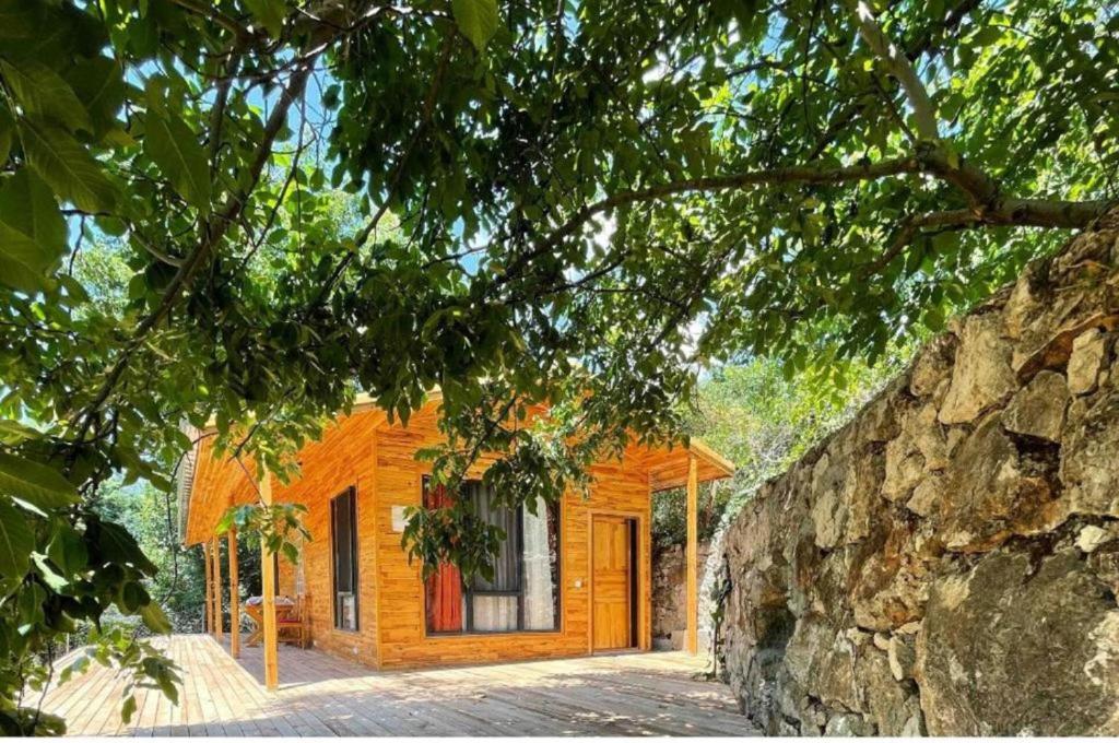 a wooden cabin with a stone wall next to it at Ece Hanı Bungalow Hotel in Yaka