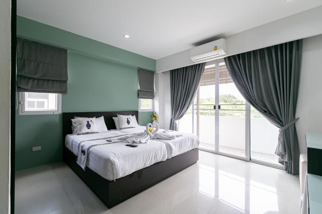 a bedroom with a large bed and a large window at Ruan Plaisoi Apartment in Bangkok