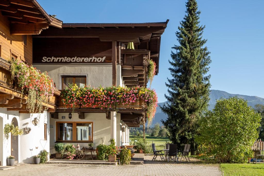 un edificio con flores a un lado. en Apartment-Pension Schmiedererhof, en Sankt Johann in Tirol