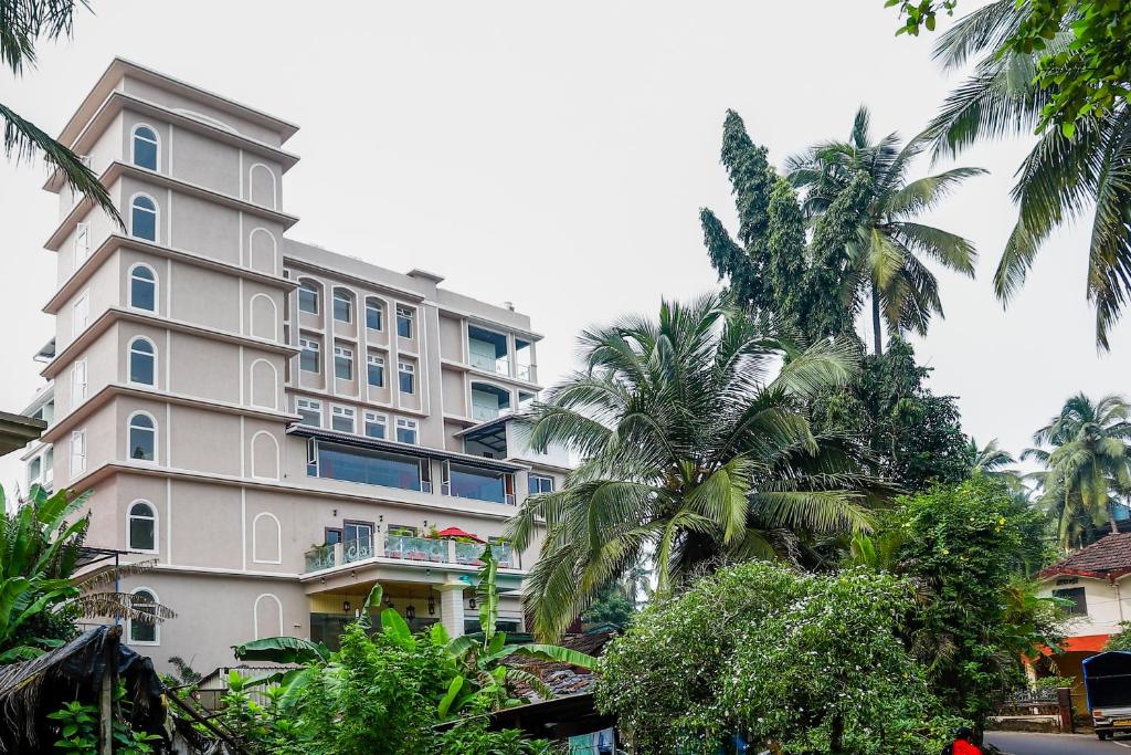 a tall building with palm trees in front of it at The Avenue Grand in Calangute