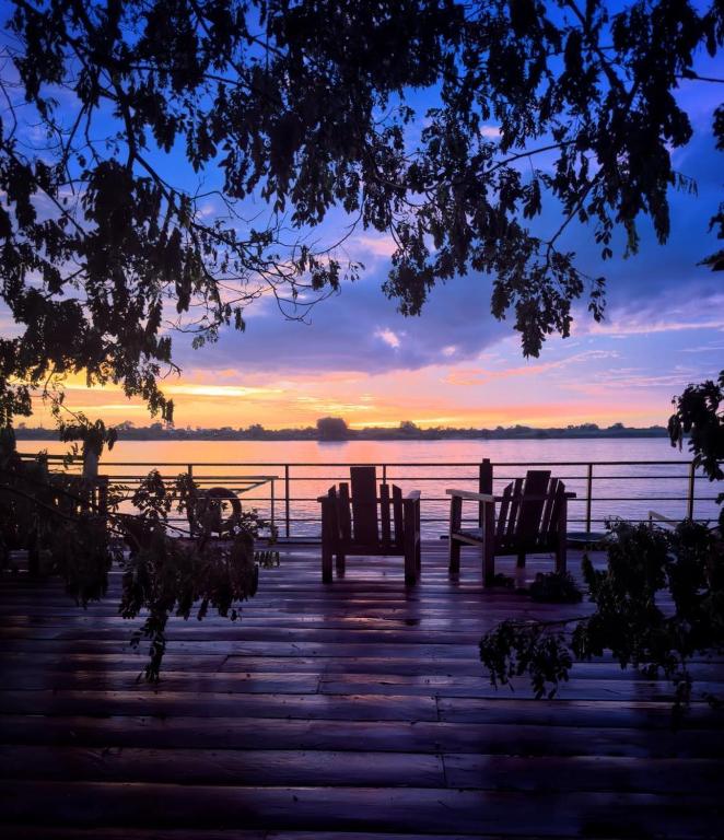 a sunset over the water with benches on a dock at Blue Indigo yoga Cambodia in Phnom Penh