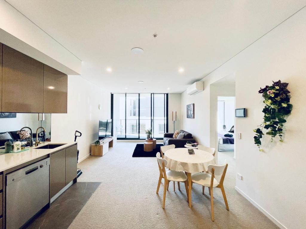 a kitchen and a living room with a table and chairs at Spacious1 BR@waterfront Olympic Park_free carpark in Sydney