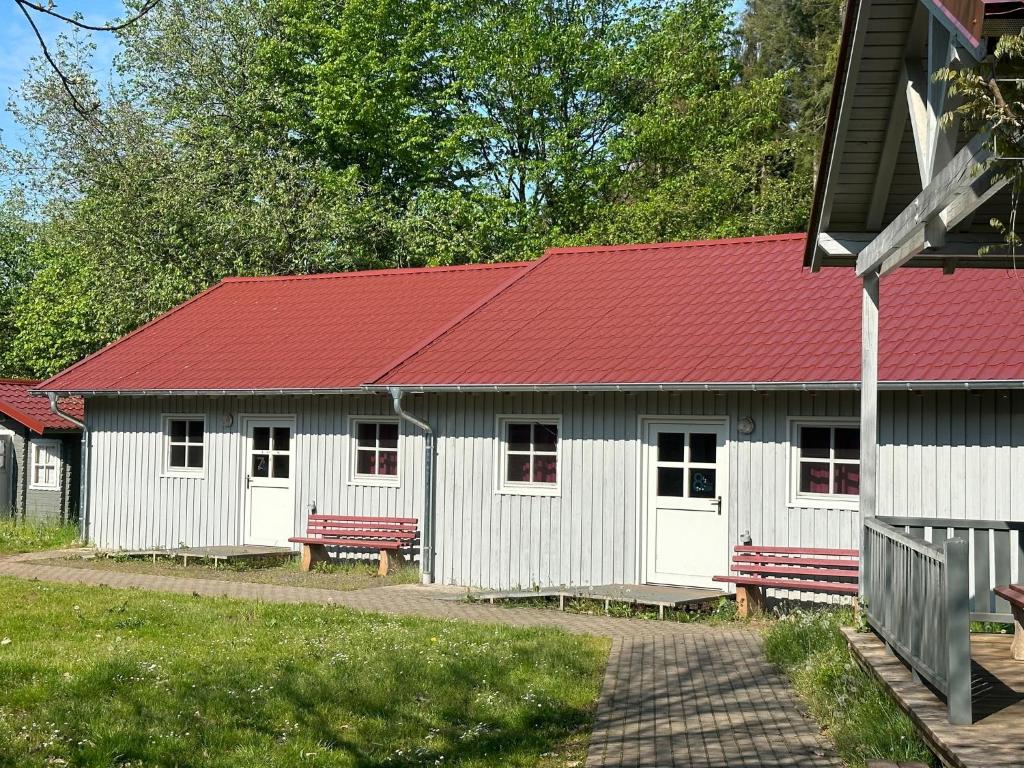 a white building with a red roof and benches at ZeitFürMich in Losheim