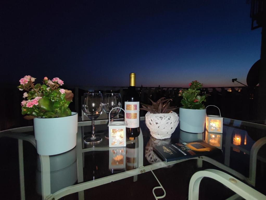 a table with wine glasses and flowers on a balcony at La casa sui tetti in Catania