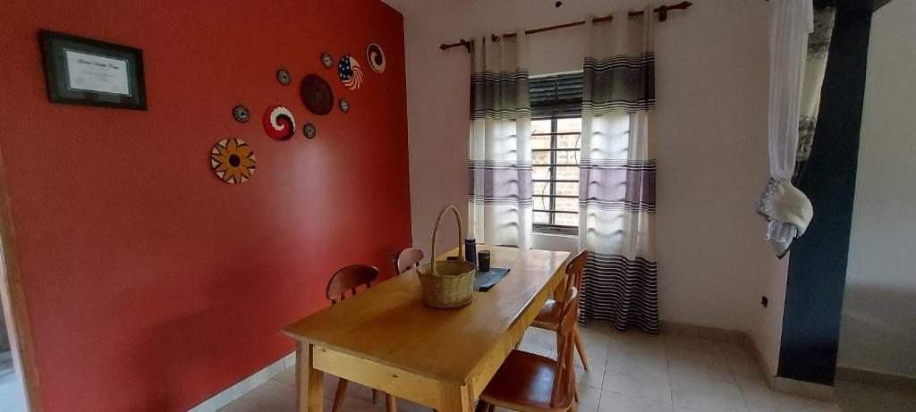 a dining room with a wooden table and a red wall at Lavila. Fully furnished 2 bedroomed house. Located in busukuma, wakiso Uganda. in Gayaza