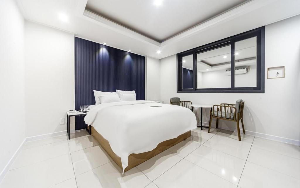 a bedroom with a large white bed and a window at Rium Hotel in Mokpo