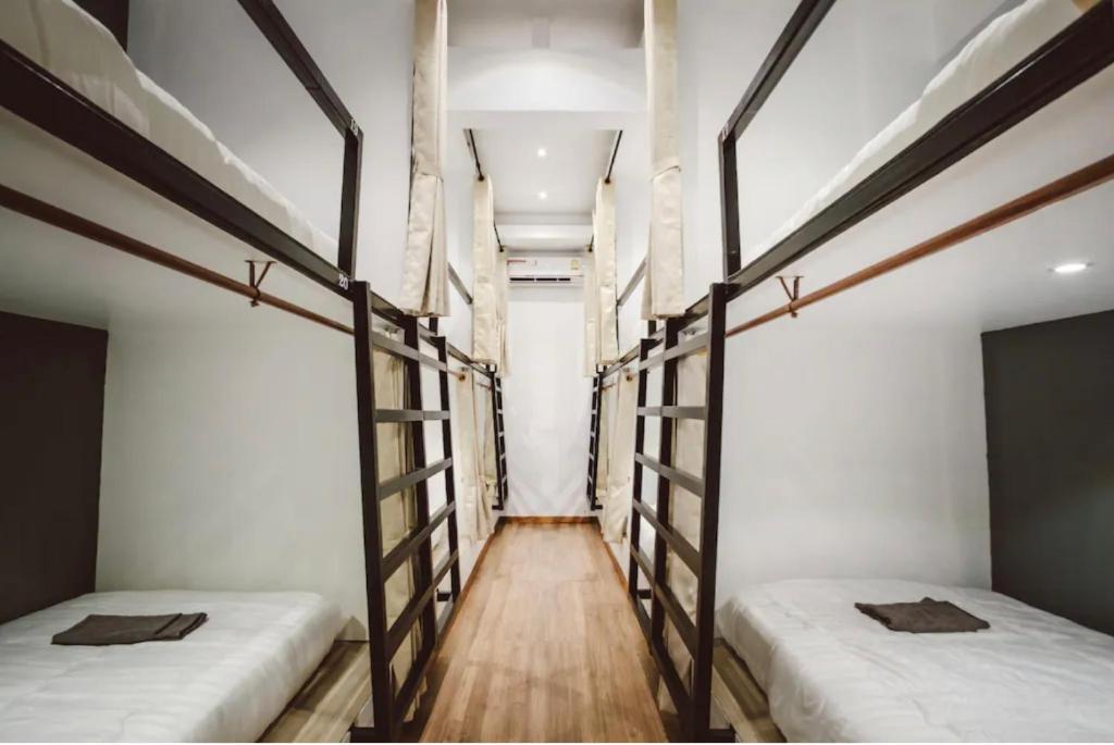 パーイにあるDANG HOSTELの白い壁とウッドフロアの客室で、ベッド2台が備わります。