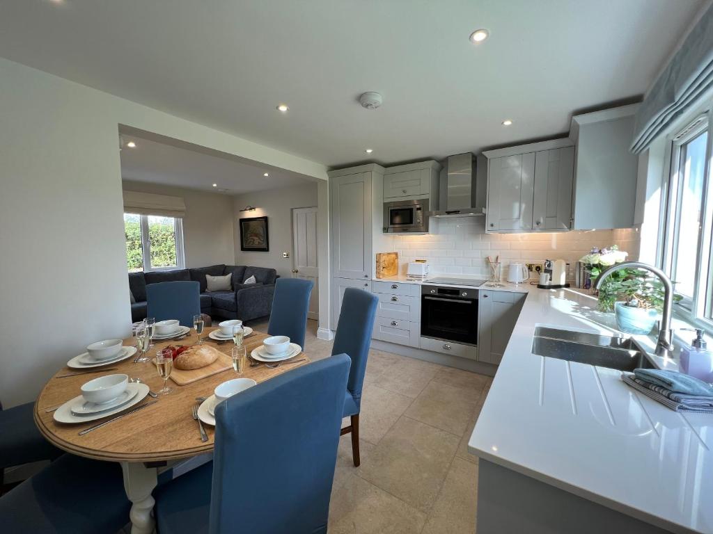 cocina y comedor con mesa de madera y sillas azules en Dell View - Charming & Cosy en Bentley