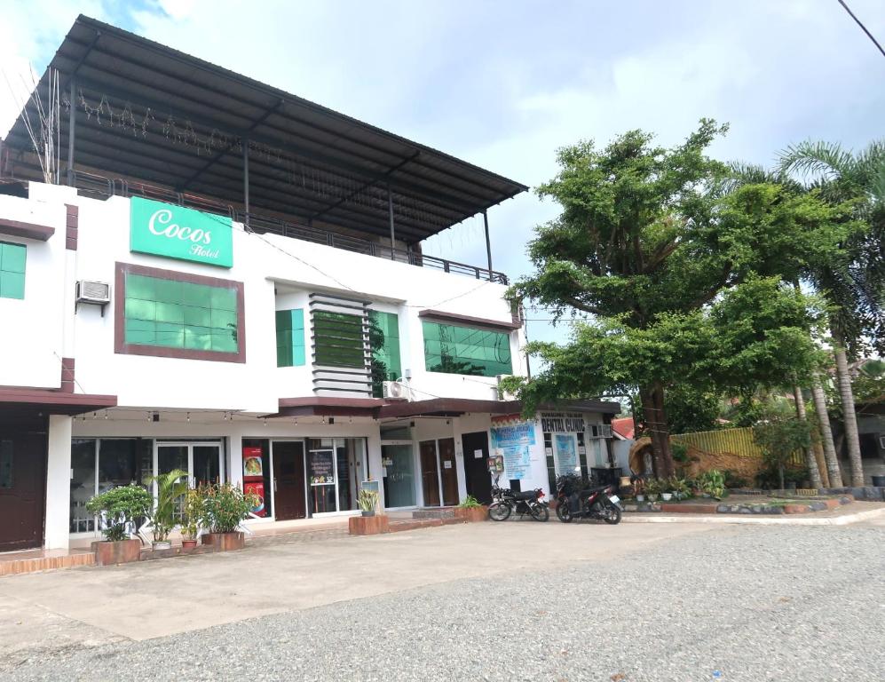 a white building with a green sign on it at COCOS HOTEL in Compostela