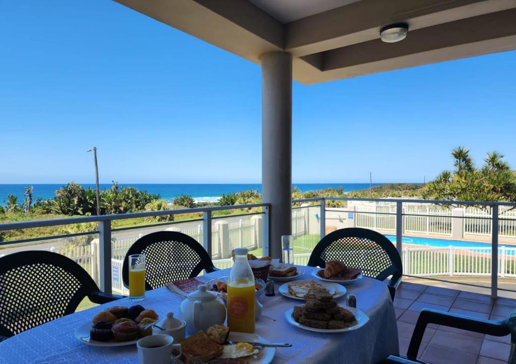 a table with food on top of a balcony with the ocean at Casa Uvongo 110 in Uvongo Beach
