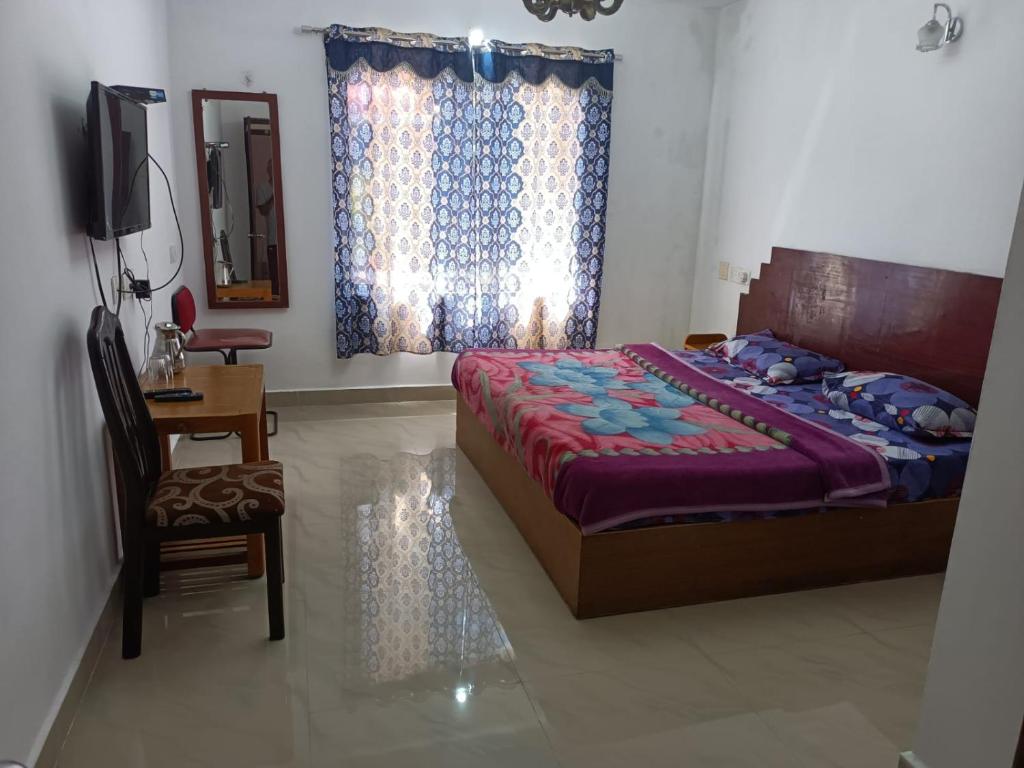 a bedroom with a bed and a chair and a television at Hill Heaven Home Stay in Kodaikānāl