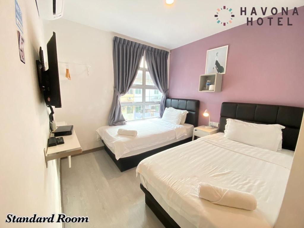 a hotel room with two beds and a window at Havona Hotel - Kulai in Kulai