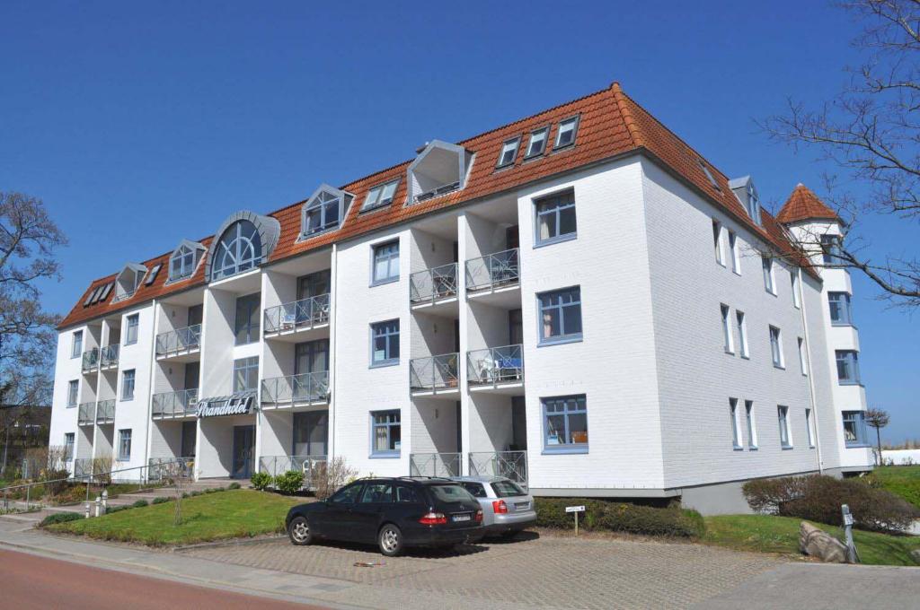 un grande edificio bianco con un'auto parcheggiata di fronte di Strandhotel Appartement Nr 33 a Niendorf