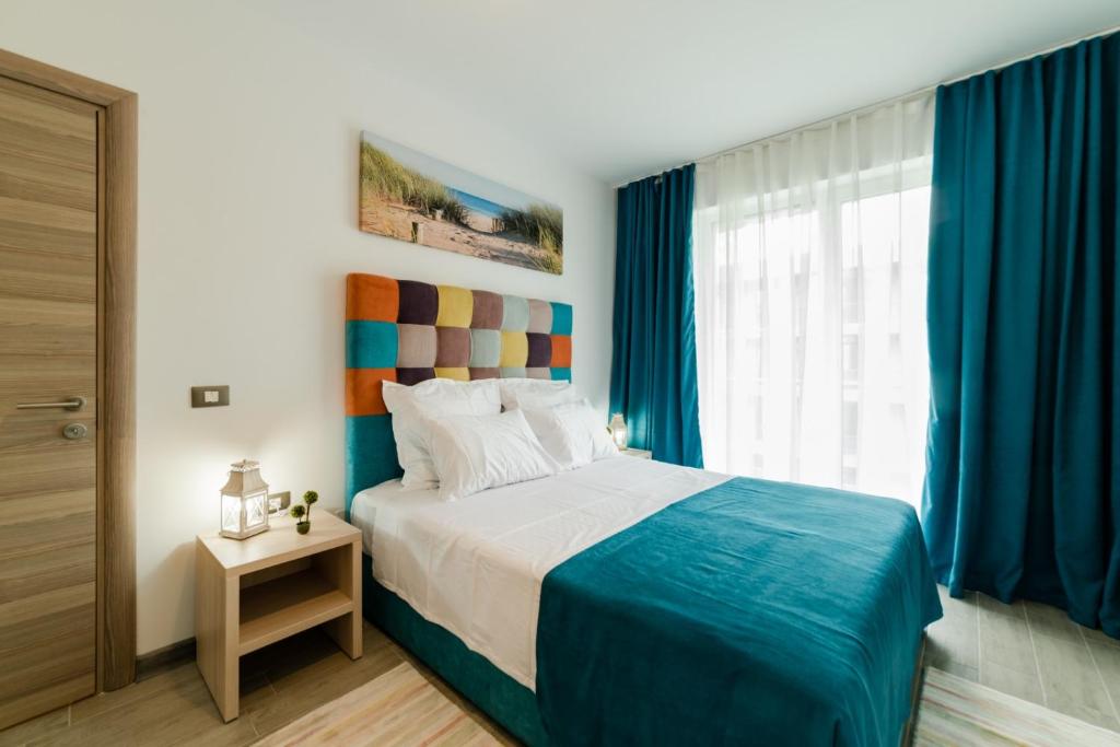 a bedroom with a bed with blue curtains and a window at Alezzi Luxury Apartments & Spa Center in Mamaia Sat/Năvodari