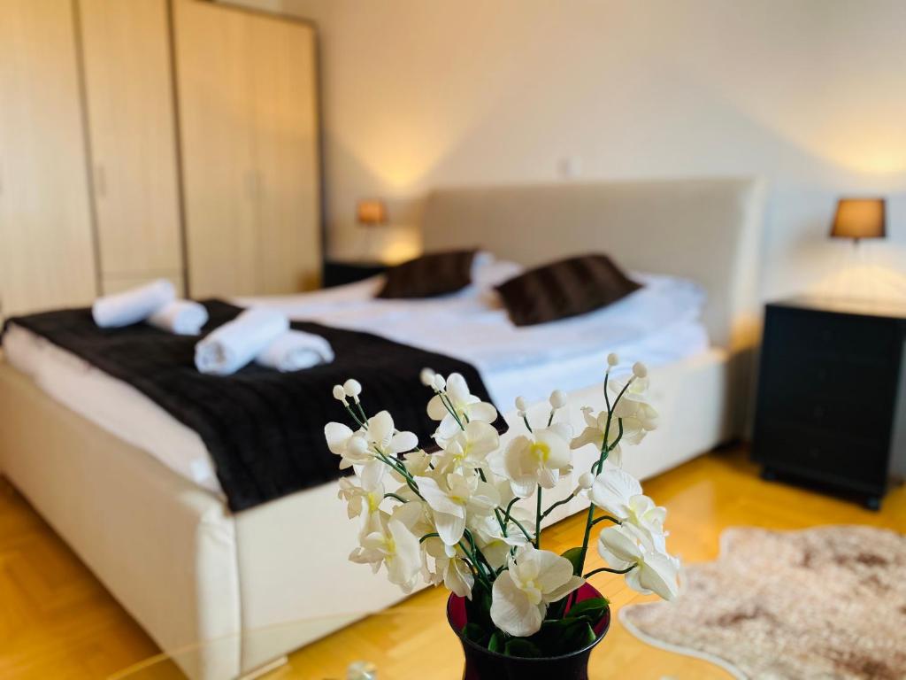 1 dormitorio con 2 camas y un jarrón de flores en Apartment Deluxe Otoka, en Sarajevo