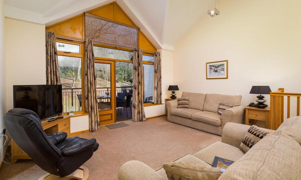 a living room with a couch and a television at Keswick Bridge Lodge Resort in Keswick