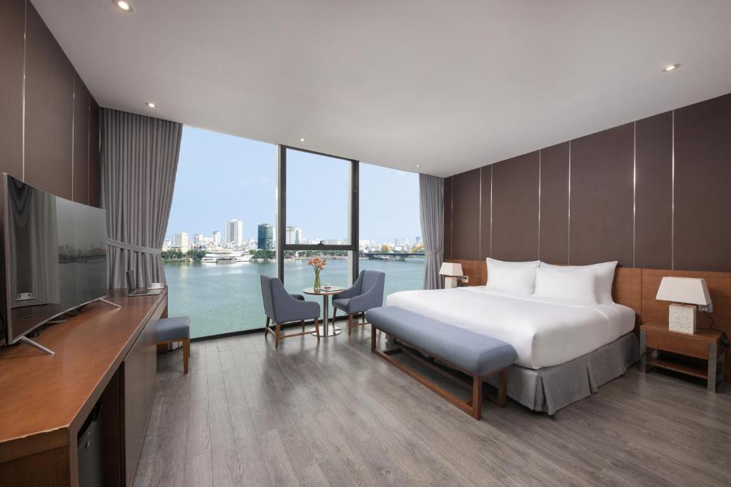 a bedroom with a bed and a view of the water at Avora Hotel in Da Nang