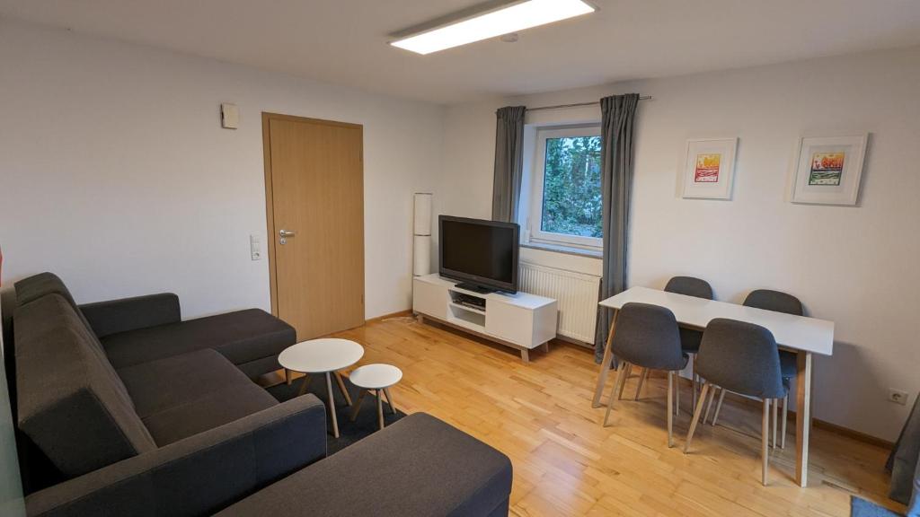 een woonkamer met een bank en een tafel met stoelen bij NEU! Moderne Ferienwohnung Ulm in Ulm