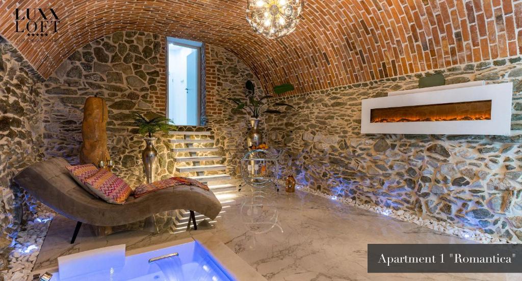 a living room with a couch and a stone wall at LUXXLOFT Luxusapartments Wetzlar in Wetzlar