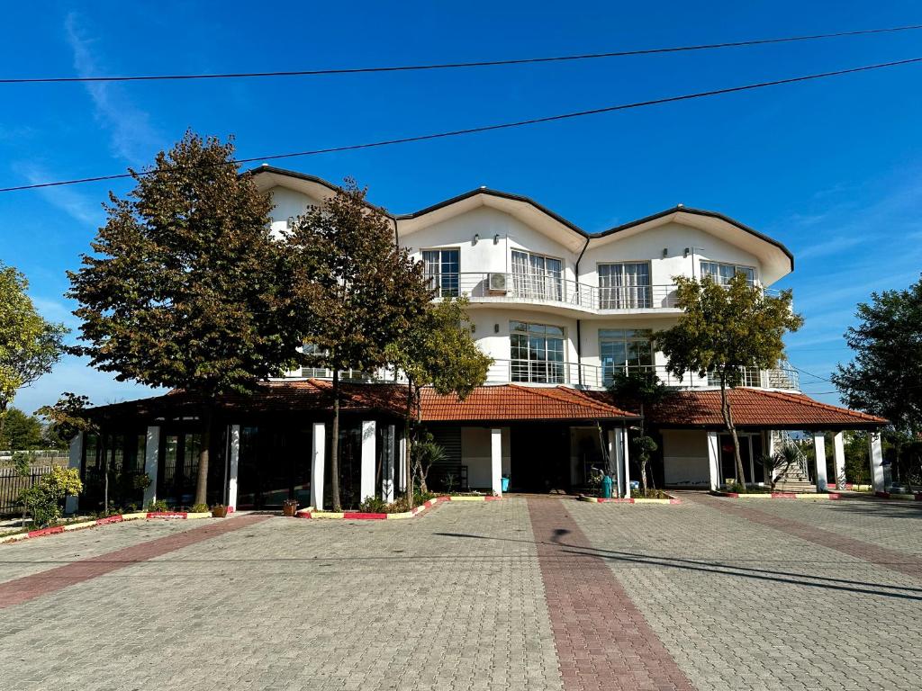 a large white building with a tree in front of it at Room rental in Velipojë