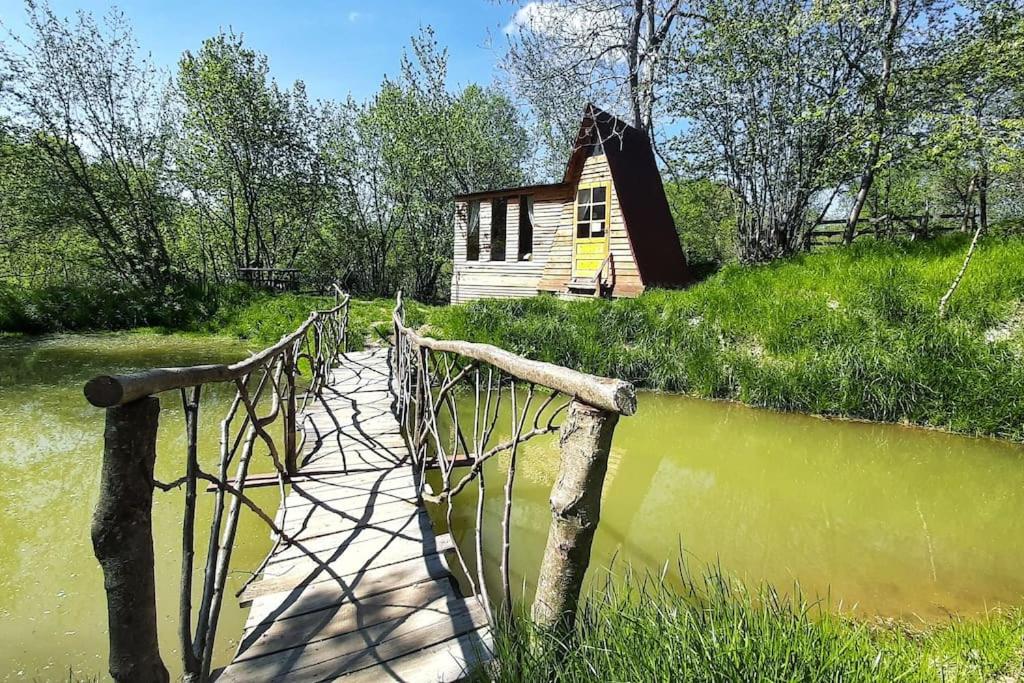 a bridge over a river with a house in the background at Fisherman's Cabin (Friendship Land) in Şelari