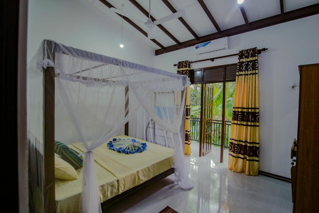 1 dormitorio con cama con dosel y balcón en King Coco Villa Hikkaduwa, en Galle