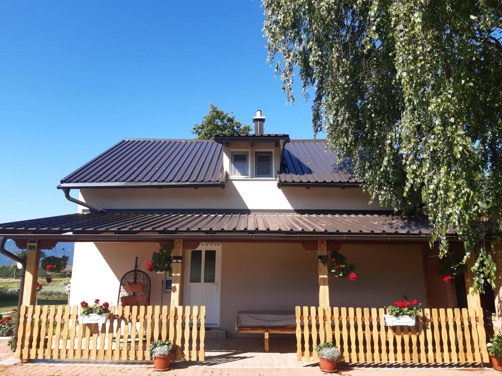 a house with a black roof and a fence at Kuća za odmor Lika in Gospić