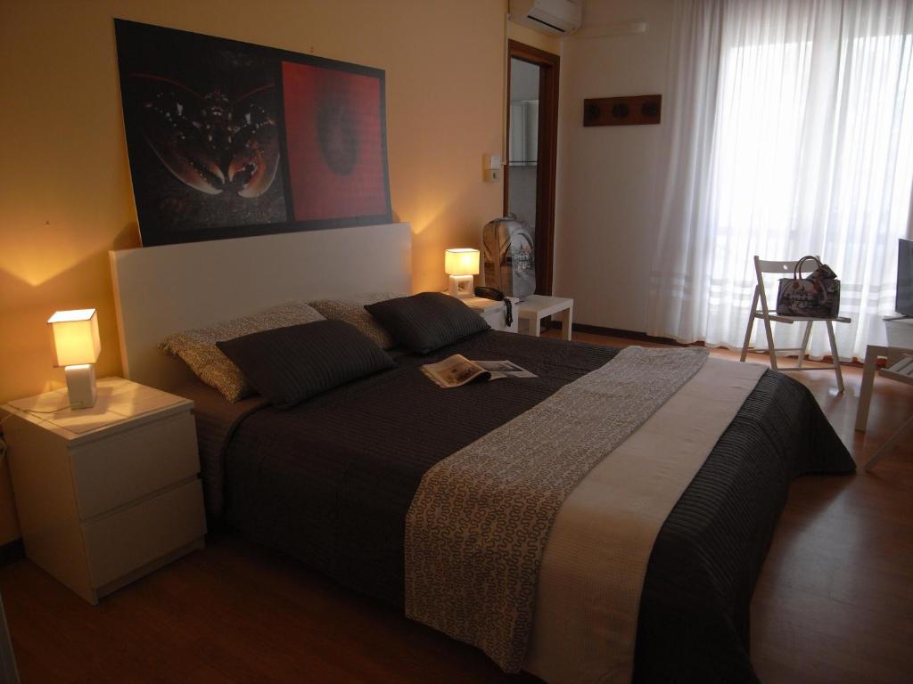 um quarto com uma cama, 2 candeeiros e uma cadeira em Hotel Moreri em Grado