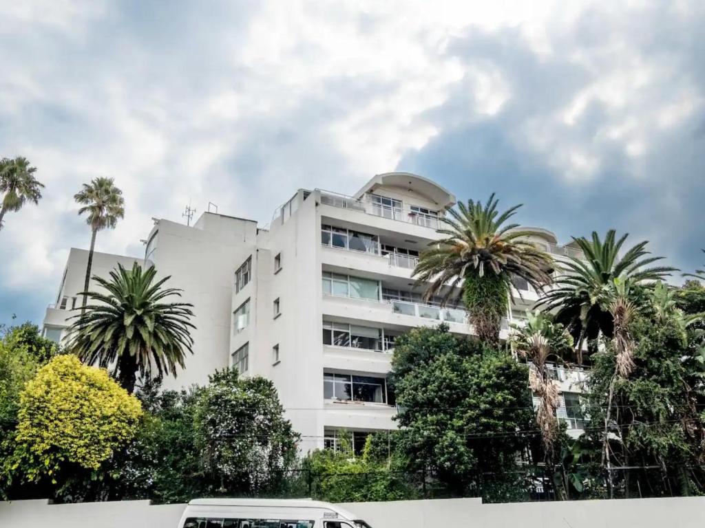 a white building with palm trees in front of it at Lovely 3 Bedroom Unit Sandton in Johannesburg