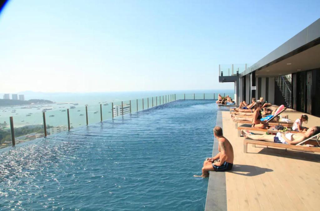 a group of people sitting on the edge of a swimming pool at Best Location In Pattaya, Sky Pool & Infinity Edge in Pattaya