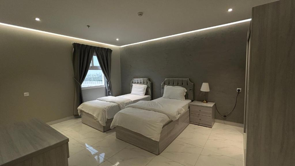 1 Schlafzimmer mit 2 Betten und einem Fenster in der Unterkunft لاقونا للشقق المخدومة in Al-Hasa