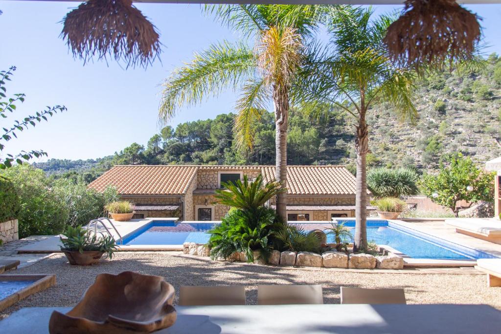 a house with a swimming pool and palm trees at Villa Can Rasca in Caimari