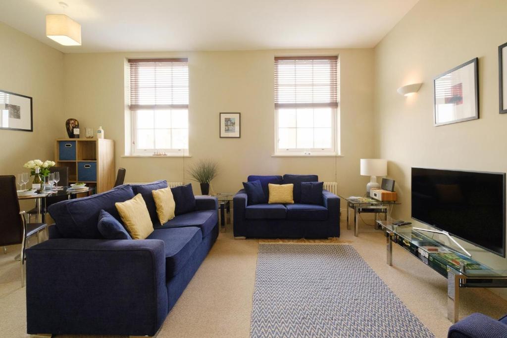 Il comprend un salon doté de canapés bleus et d'une télévision à écran plat. dans l'établissement Beachcomber - Aldeburgh Coastal Cottages, à Aldeburgh