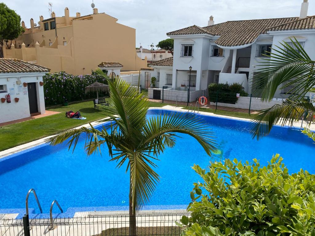 een villa met een zwembad en een palmboom bij Apartamento Costa de Sancti Petri by Chiclana Dreams in Novo Sancti Petri