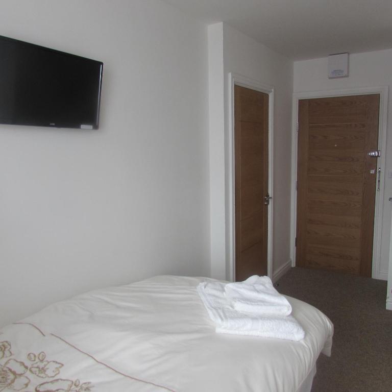 a white bed in a room with a flat screen tv at Lord Nelson Hotel in Rhymney