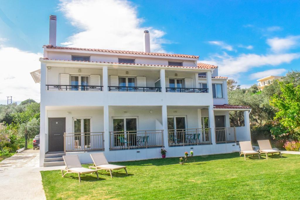 une maison blanche avec des chaises sur la pelouse dans l'établissement Ktima Holiday House, à Skiathos Chora