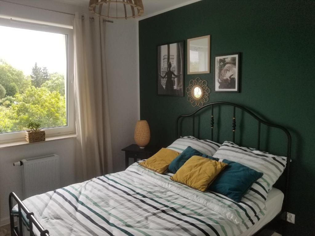 um quarto com uma cama com paredes verdes e uma janela em FORT Apartament em Malbork