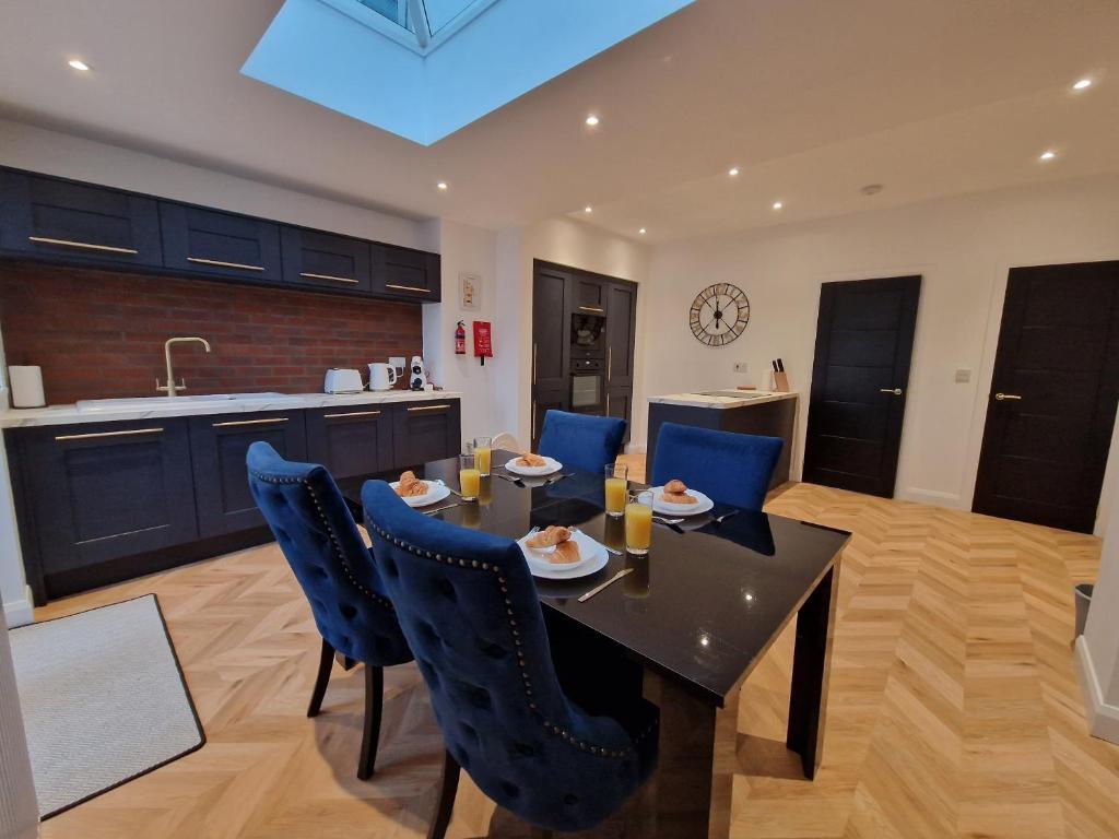 uma cozinha e sala de jantar com uma mesa e cadeiras azuis em 3 Bedroom Stylish Home Merthyr em Merthyr Tydfil