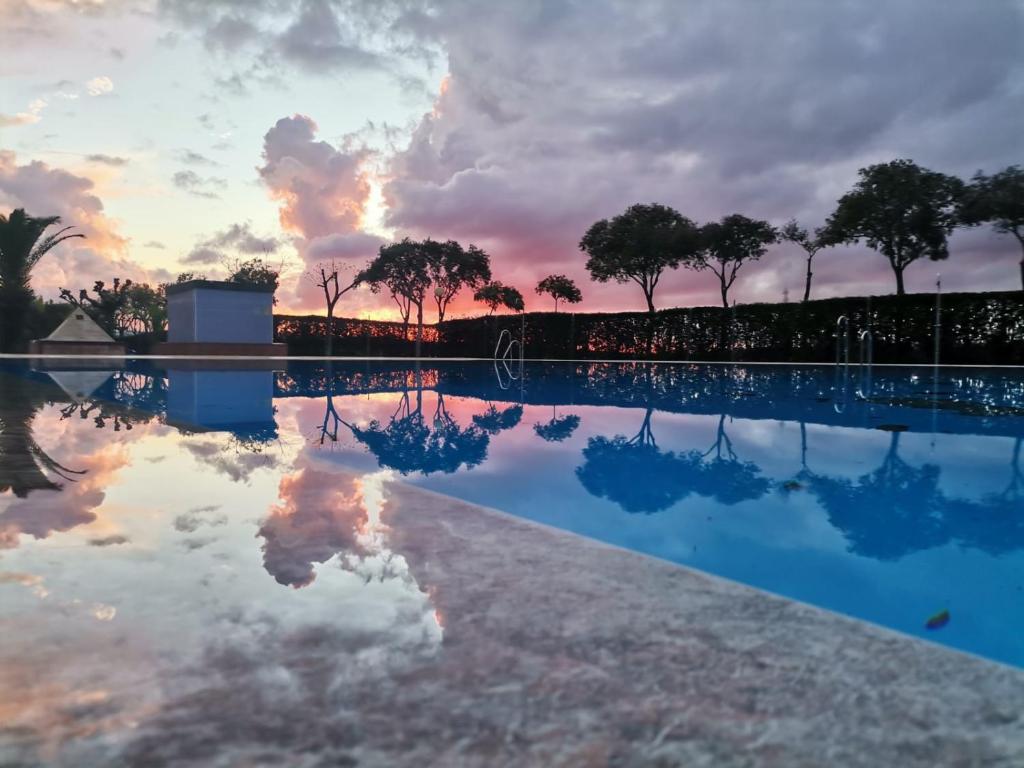 a sunset over a swimming pool with trees in the background at Camping Carlos III in La Carlota