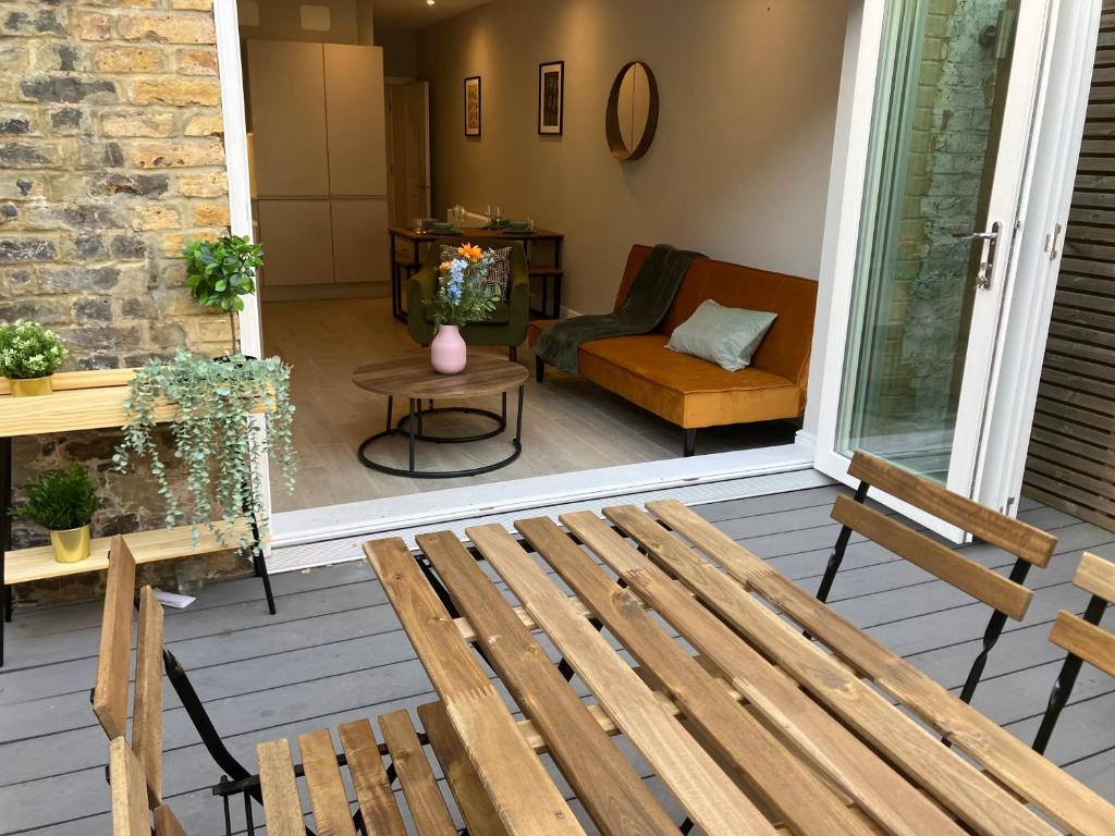 a porch with a wooden bench and a chair at Spectacular 2 Bed Apartment With Lovely Terrace - 1 The Southwell in London
