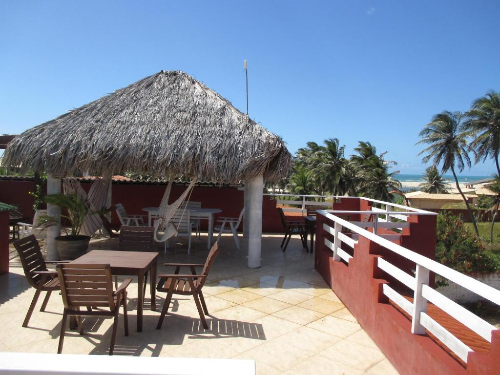 een patio met een tafel en stoelen en een rieten parasol bij Sol da Barra in Barra Nova