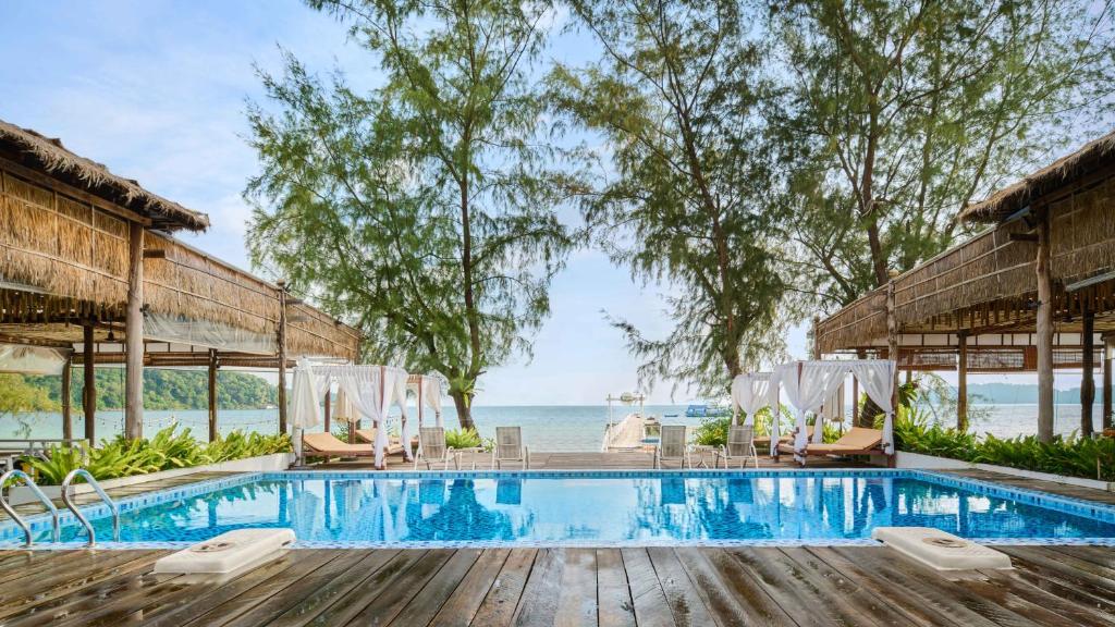 高龍撒冷島的住宿－Eden Beach Resort by EHM，一个带椅子的游泳池,背景是大海