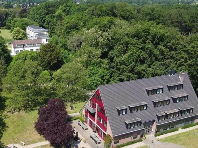 une vue aérienne sur une grande maison rouge avec des arbres dans l'établissement Fletcher Hotel Landgoed Huis te Eerbeek, à Eerbeek