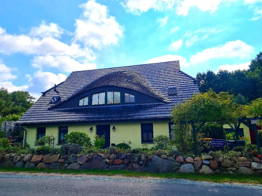 una casa con techo de gambrel y pared de piedra en Hus Sünnschien, en Alt Reddevitz