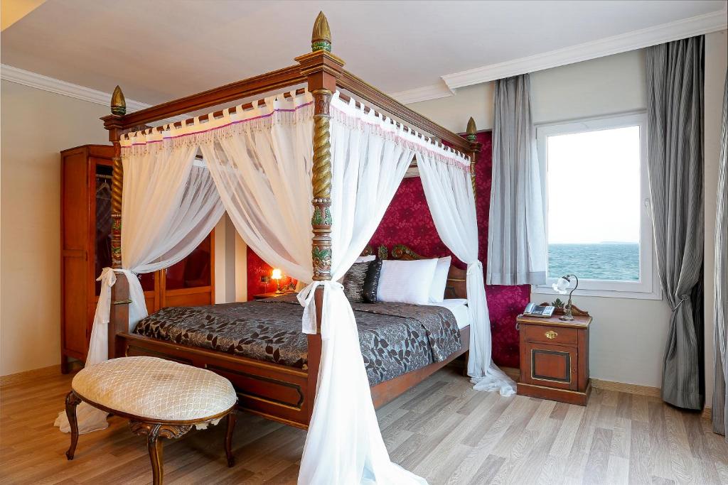 a bedroom with a canopy bed and a window at URLA PERA HOTEL in Urla