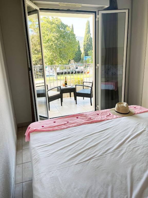 - un lit avec chapeau dans une chambre avec balcon dans l'établissement Appartement 312 supérieur - LES SUITES DE ROBINSON - Résidence avec piscine en bord de Siagne, à Mandelieu-La-Napoule, à Mandelieu-la-Napoule