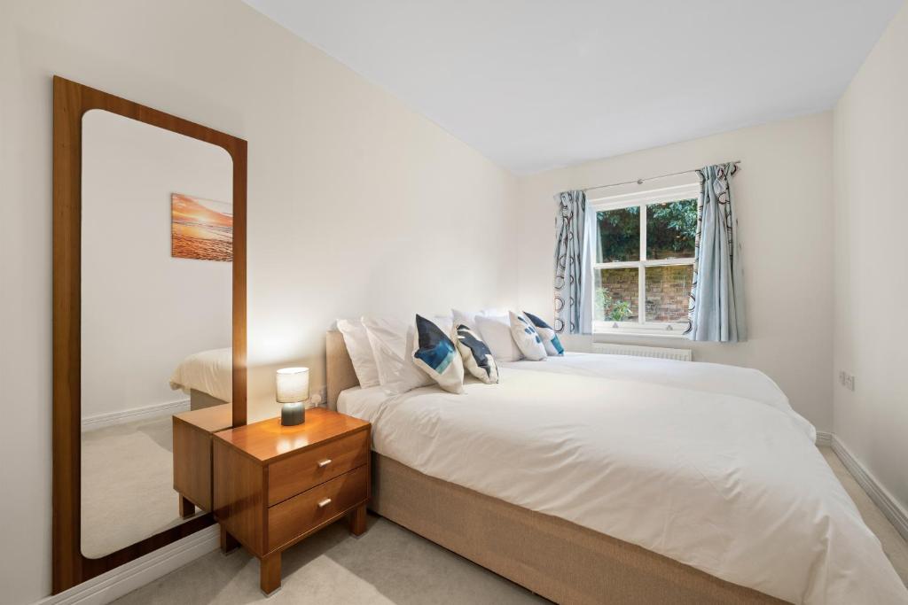 1 dormitorio con espejo grande y cama en Molesey Apartments, en East Molesey