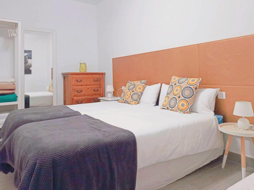 a bedroom with a large white bed and a wooden headboard at Live La Laguna Gracia in Las Lagunas