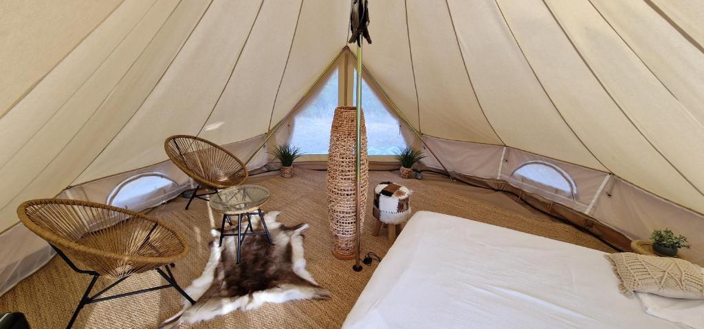 a tent with two chairs and a cat in it at Tente Lodge TIPI A 1H de Nice CLAIR DE LUNE in Bézaudun-les-Alpes